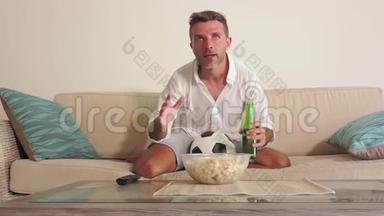 30岁的男子在电视上看<strong>足球赛</strong>，喝着啤酒，拿着足球庆祝进球